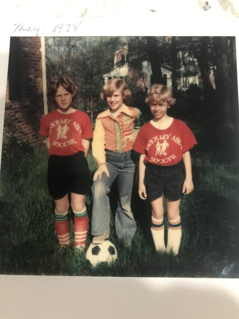 Three young boys standing near a soccer ball
